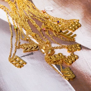 Close-up of assorted gold stainless steel angel number pendants with sparkling crystals