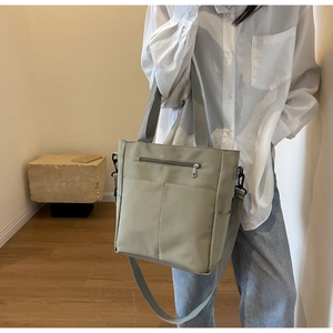 Detail of light green canvas tote bag with front zipper pocket and adjustable strap