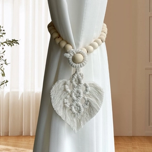Hand-woven boho curtain tieback featuring wooden beads and leaf fringe on a white curtain