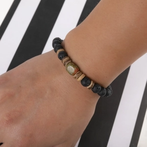 Detail of beaded bracelet with black lava rock and wood beads on a person wrist