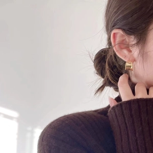 Close-up of elegant gold polished hoop earrings worn by a model in soft natural light
