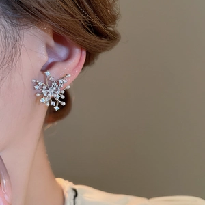 Close-up of snowflake stud earrings with pearls and zircons on female model