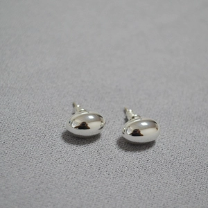 Minimalist silver mirror polished oval stud earrings on a grey textured fabric background