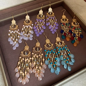 Top view of five pairs of bohemian beaded tassel earrings on a brown velvet jewelry tray