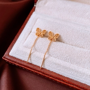 Detailed macro view of 18K gold-plated butterfly threader earrings with hollow design