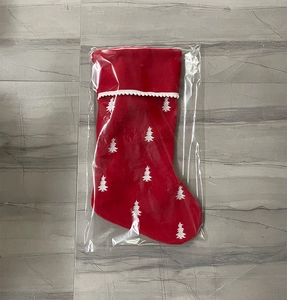 Detail view of a large red Christmas stocking with tree embroidery in plastic packaging