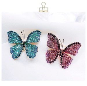 Detail of vibrant butterfly brooches with gradient crystals and metal base on fabric