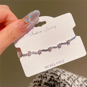 Detail of silver wavy bracelet featuring pink zircons and rhinestones on a card