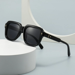 Chic black round sunglasses with gold star accents on a stylish geometric stand