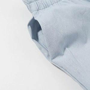 Detail of light blue cotton linen pants featuring elastic waistband and side pocket