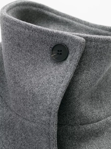 Close-up of dark grey wool coat lapel featuring a detailed brown textured resin button