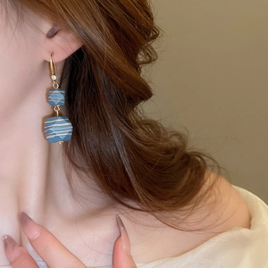 Close-up of vintage blue geometric earrings with gold stripes worn by a model