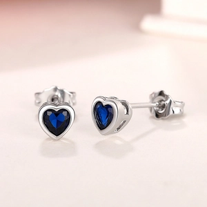 Macro shot of silver heart earrings with faceted blue stones and polished finish