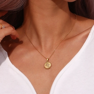 Close-up of a gold star compass pendant necklace with a diamond center on a model