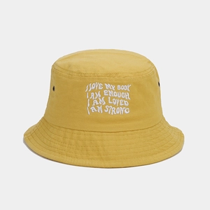 Detail of yellow cotton bucket hat featuring white motivational letter embroidery and air vents