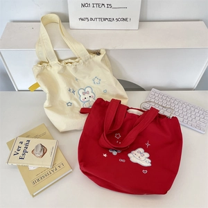 Detail of embroidered canvas drawstring bags with cute rabbit patterns in cream and red