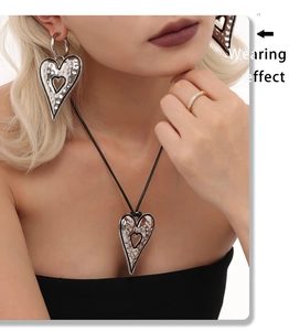 Close-up of hammered heart-shaped necklace and earrings on model for styling detail