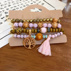 Detail of bohemian multilayer bracelet with tree of life charm and pink tassel