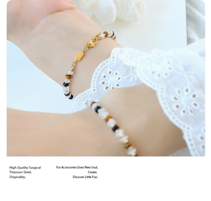 Détail d'un bracelet en perles avec chaîne en acier titane doré et fermoir mousqueton