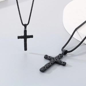 Macro detail of a black stainless steel cross pendant with punk chain relief texture