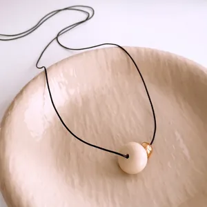 Ethnic style wax rope necklace with large cream resin pendant and gold metal bead detail