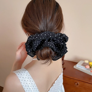Close-up of a large black and white polka dot chiffon scrunchie worn on a hair bun