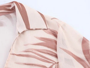 Detail of V-neck collar and palm leaf print on lightweight beige chiffon blouse