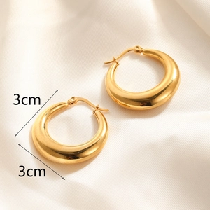 Close-up of 3cm polished gold plated hoop earrings on luxurious white silk background