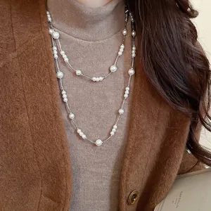 Elegant double-layered faux pearl necklace with silver chain on a warm knit sweater