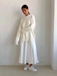 Detail of white oversized distressed knit hoodie with pink embroidery and silk pleated skirt