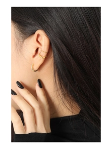 Close-up of three-piece gold earring set with zircon-inlaid hoop and textured ear cuffs