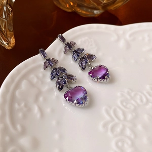 Gros plan de boucles d'oreilles cœur en cristal violet sur un plateau en céramique