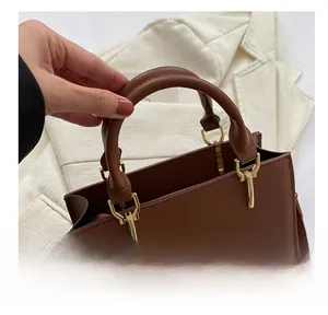 Close-up of brown textured leather handbag with dual circular handles and gold hardware