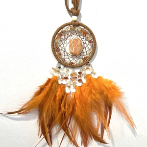 Detail of handmade dreamcatcher with orange feathers, brown weave and natural pink crystal