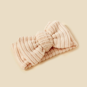 Close-up of beige ribbed knit baby headband with a decorative bow detail