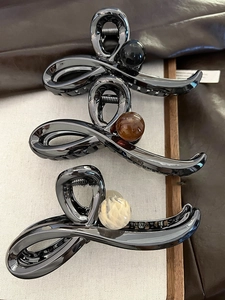 Close-up of twist design hair claws with glossy metal finish and elegant marble beads