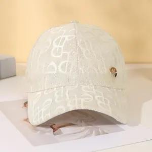 Detail of beige baseball cap featuring monogram jacquard fabric and crystal metal logo