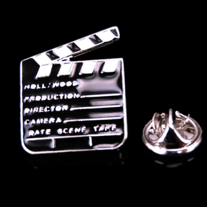 Detailed close-up of a movie clapperboard enamel pin with standard director terminology