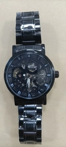 Détail d'une montre mécanique automatique noire avec mouvement squelette doré visible