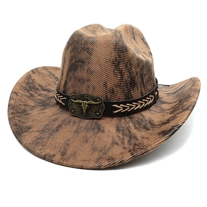 Detail of vintage brown cowboy hat with leather band and metal bull head emblem buckle