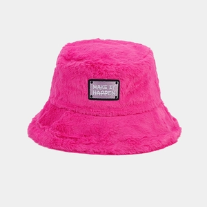Gros plan du bob en peluche rose avec un écusson noir brodé Make It Happen