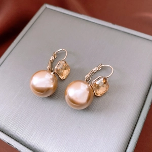 Detailed macro view of champagne pearl and geometric crystal drop earrings on a grey tray
