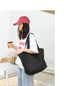 Black canvas tote bag on female model showing large capacity and casual daily style