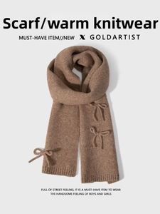 Detail of a brown knitted scarf featuring three decorative 3D bows on a soft wool blend texture