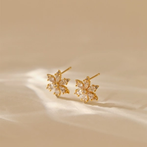 Detail of 18K gold-plated floral stud earrings with sparkling cubic zirconia on silk