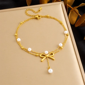 Detail of a gold-layered anklet featuring white pearls and an elegant bow charm detail