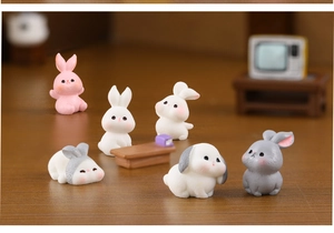 Macro shot of 6 mini resin rabbit figurines in various poses on a wooden tabletop