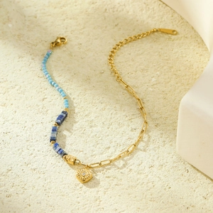 Detail of beaded steel bracelet with blue stones and a zircon sun pendant charm