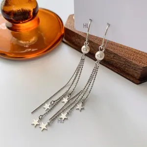Vue détaillée de boucles d'oreilles en argent S925 avec perles et pompons en étoile