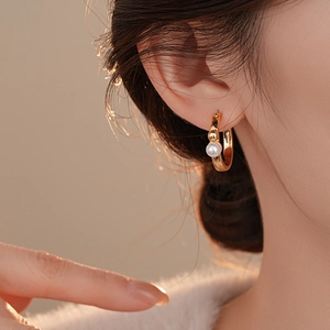 Gros plan d'une boucle d'oreille créole géométrique plaquée or 14K avec une perle blanche